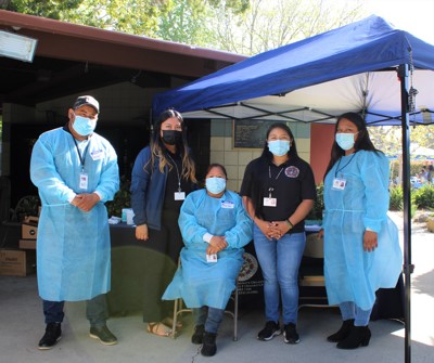 MICOP staff members wearing medical smocks and masks at MICOP event.