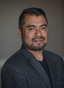 Arcenio Lopez wearing a charcoal blazer and black shirt.